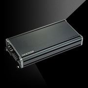 Angled top view of KICKER CXA1800.1 car amplifier showing compact chassis and terminal connections.