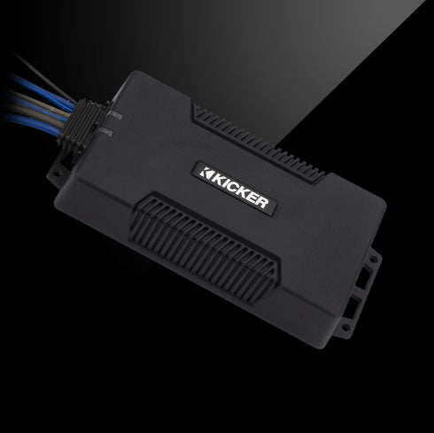 Angled view of KICKER PXA amplifier with rugged black housing and connected wiring harness.